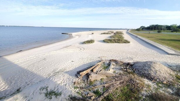 Une plage de sable fin, avec un ciel dégagé et une eau calme.