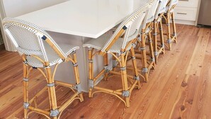 Une cuisine dotée d’un îlot central, de meubles blancs, d’un four à micro-ondes et d’une machine à café.