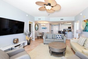A living room with a flat-screen TV, a ceiling fan, a round coffee table, and a sofa.