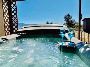 A hot tub with two glasses of blue liquid, surrounded by a wooden lattice structure. - Crane Suite/Hot Tub/BBQ/King Bed- Sleeps 4 (Ahwahnee)