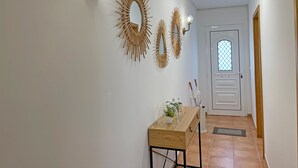 Un couloir avec une console en bois, des miroirs fixés au mur et une porte dotée d’une fenêtre.