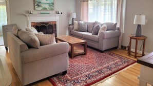 A living room with two sofas, a coffee table, a fireplace, a rug, and a lamp. - 2 bedroom ranch 1 bath situated in West Yarmouth (Yarmouth)
