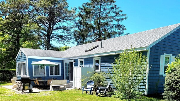 A two-story house with a covered patio, outdoor seating, and a well-maintained lawn. - 2 bedroom ranch 1 bath situated in West Yarmouth (Yarmouth)
