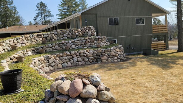 A large building with a stone retaining wall and a wooden deck.