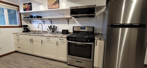 A modern kitchen with white cabinets, stainless steel appliances, a microwave, a stove, and a refrigerator.
