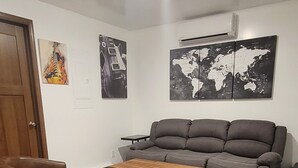 A living room with a grey sofa, two brown armchairs, a wooden coffee table, and a world map on the wall.