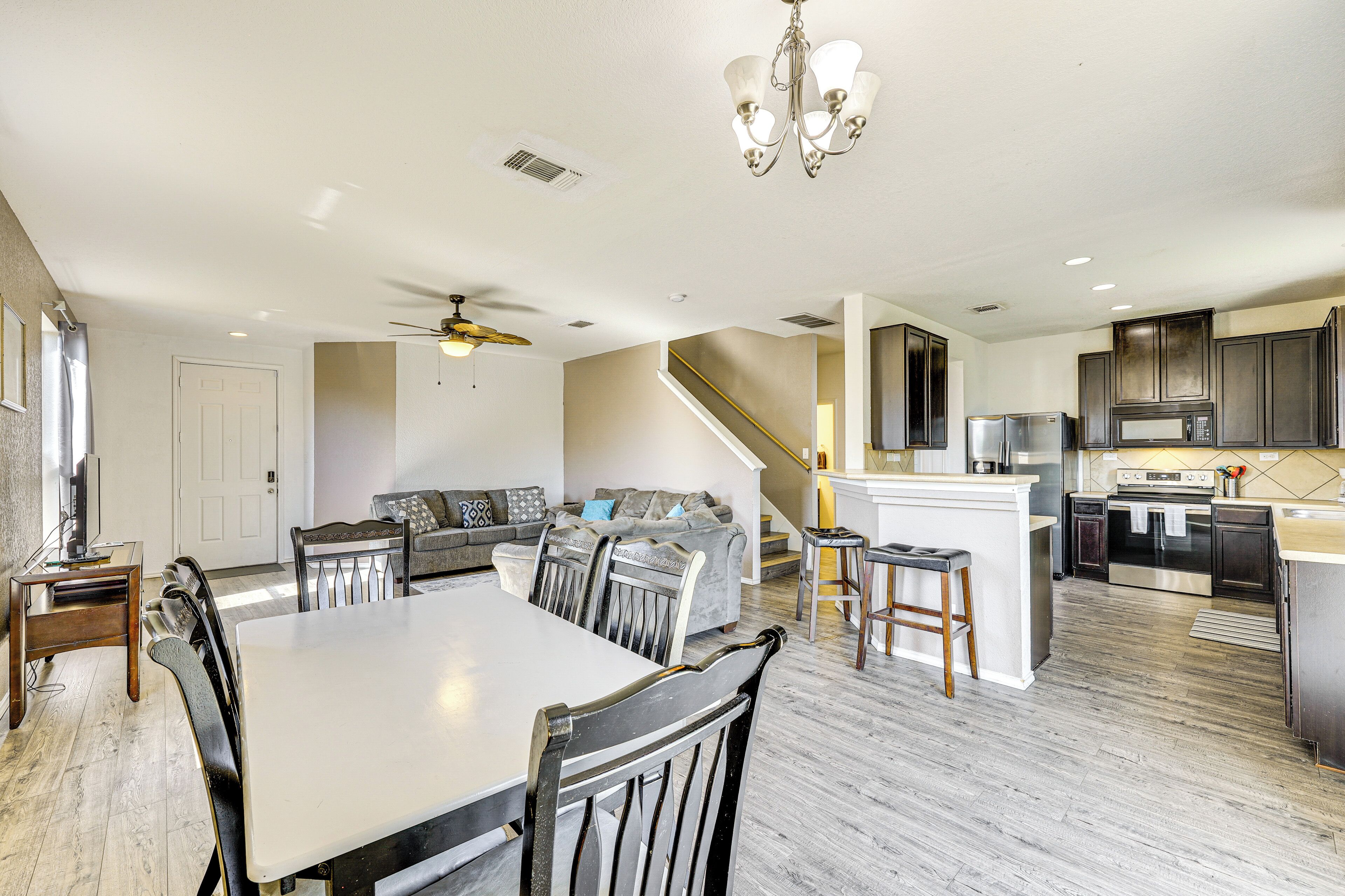 Amplia sala de estar con mesa de comedor, sillas, sofá y cocina equipada con electrodomésticos modernos.
