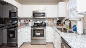 A modern kitchen with white cabinets, stainless steel appliances, granite countertops, and a built-in oven. - Beautifully Furnished, Raleigh Townhome Retreat (Raleigh)