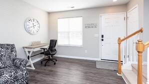 A room with a desk, a chair, a clock, a window, and a door. - Beautifully Furnished, Raleigh Townhome Retreat (Raleigh)
