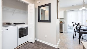 A compact kitchen with a built-in washer and dryer, a dining area with a table and chairs, and a large mirror on the wall. - Beautifully Furnished, Raleigh Townhome Retreat (Raleigh)