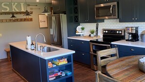 Une cuisine moderne avec des meubles de couleur sombre, des appareils en acier inoxydable et un îlot central doté de rangements.
