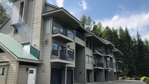 Un immeuble à plusieurs étages doté de balcons, d’un toit végétalisé et d’un espace de stationnement.