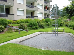 Une cour avec une sculpture en métal, une balançoire et un petit espace jardin.