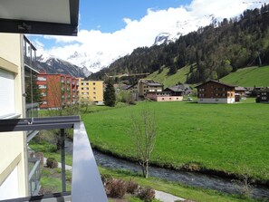 Een hotel met uitzicht op een groene vallei en bergen op de achtergrond.
