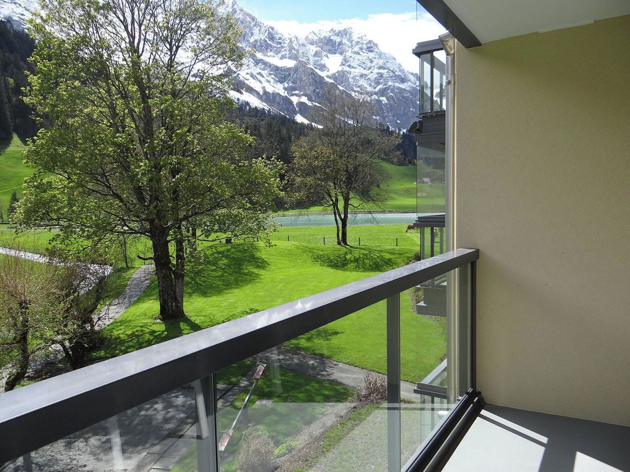 Ein Balkon mit Bergblick, einer Rasenfläche und einem See.