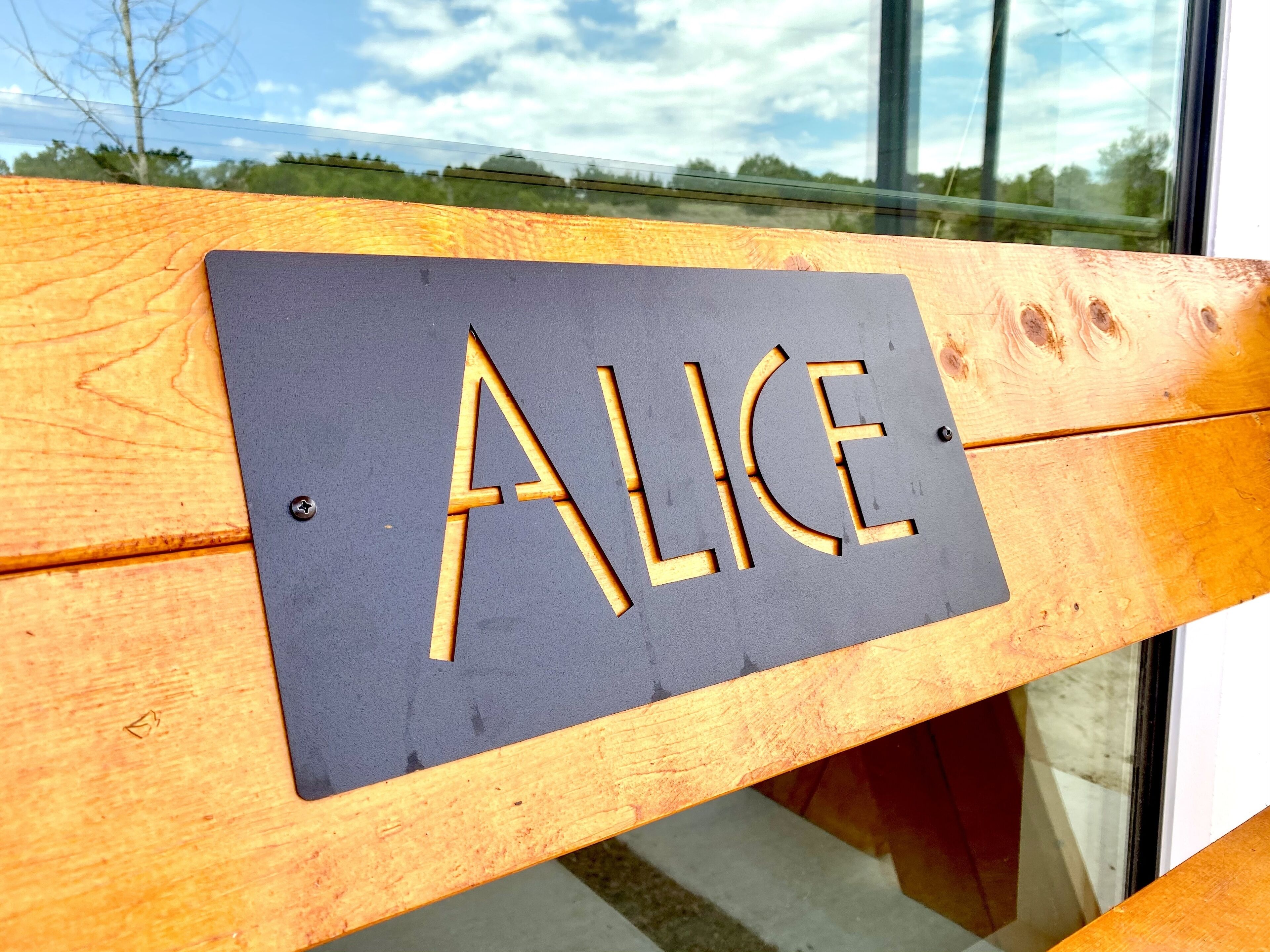 Un banc de fusta amb un rètol que diu "ALICE".