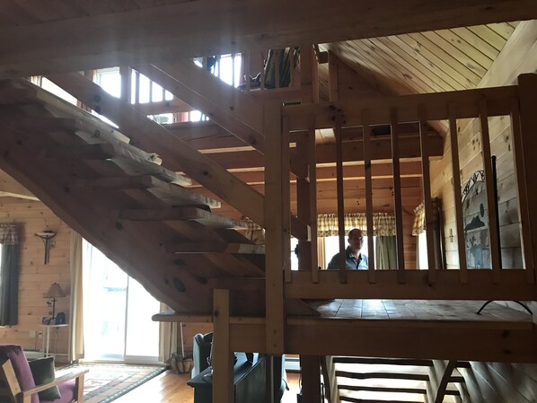 A wooden staircase with a railing, leading to an upper level. A person is visible in the background.