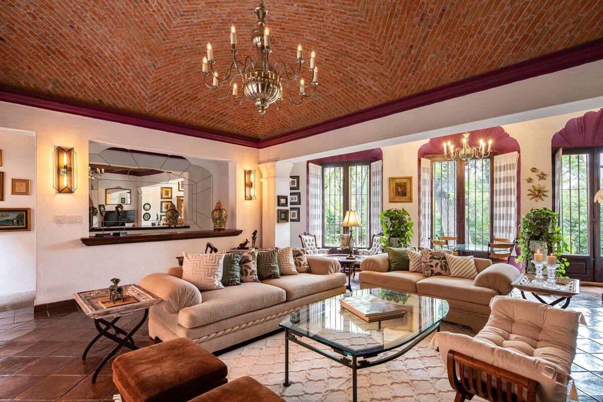 A spacious living room with a brick ceiling, a large chandelier, and a comfortable seating area with a sofa and chairs.