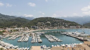 Un puerto deportivo con numerosas embarcaciones amarradas, una playa y edificios en una colina.