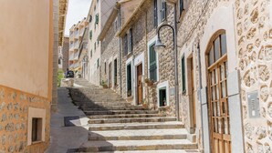 Una calle estrecha con escalones de piedra que llevan a una hilera de edificios con balcones y contraventanas.