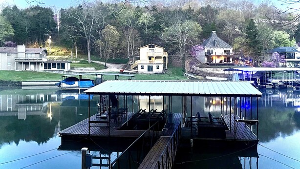 Un muelle con un área de descanso cubierta, una casa con balcón y un edificio con porche.