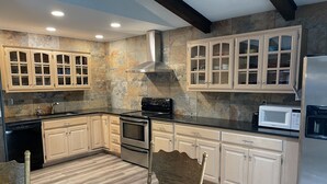Una cocina moderna con armarios de madera clara, una estufa de acero inoxidable, un microondas y un horno empotrado.
