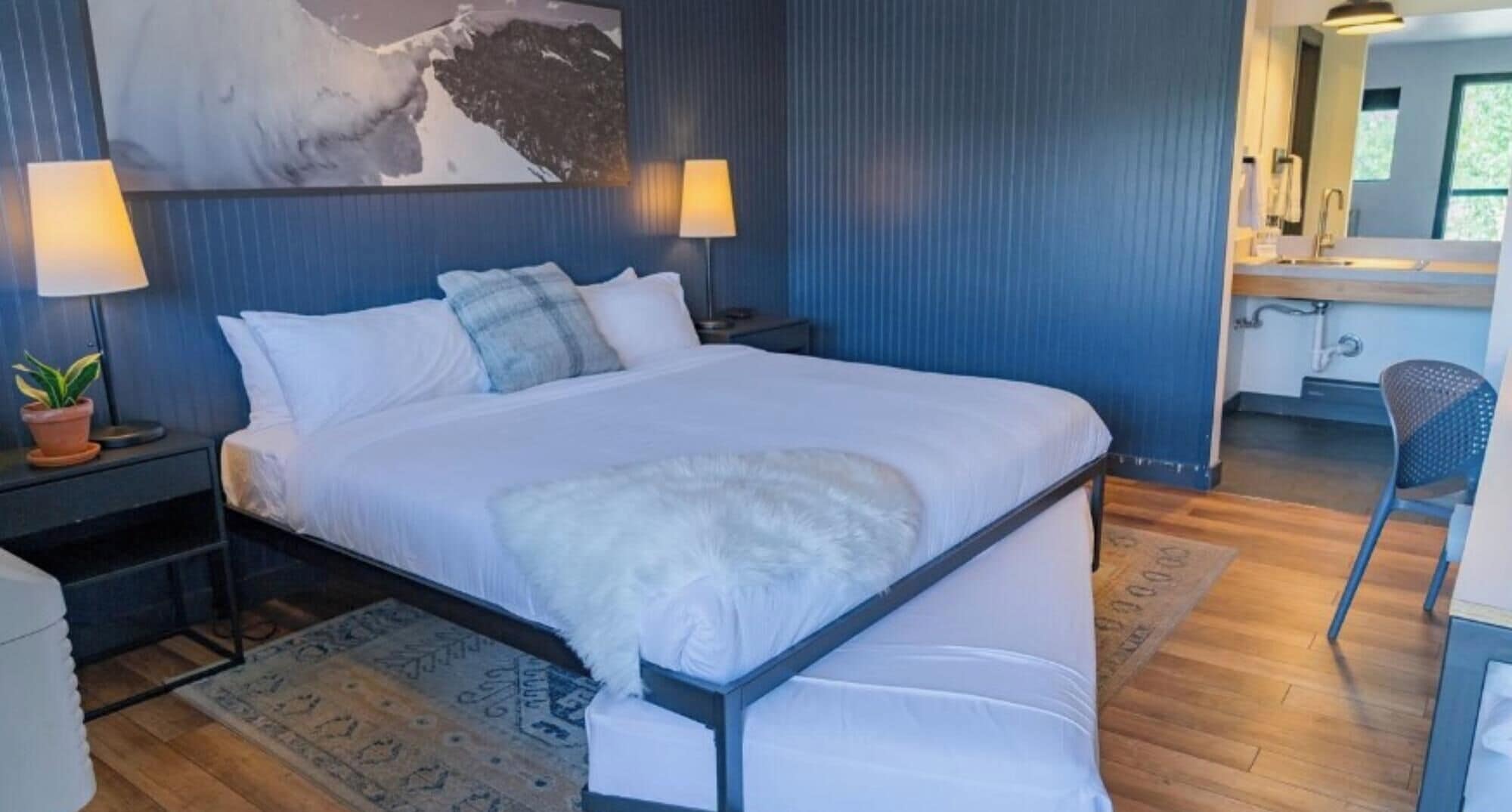 Un dormitorio moderno con una cama grande, lámparas de noche, un escritorio y una silla.
