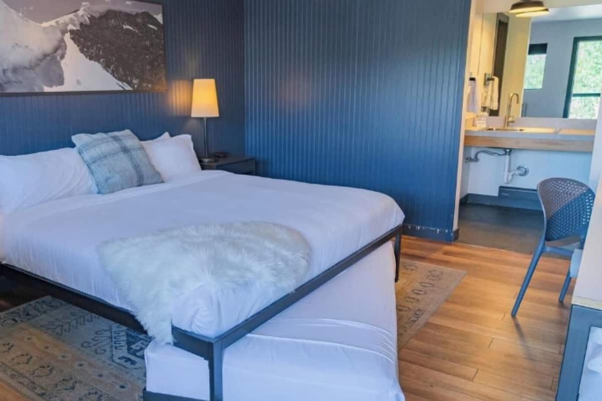 Un dormitorio moderno con una cama grande, lámparas de noche, un escritorio y una silla.