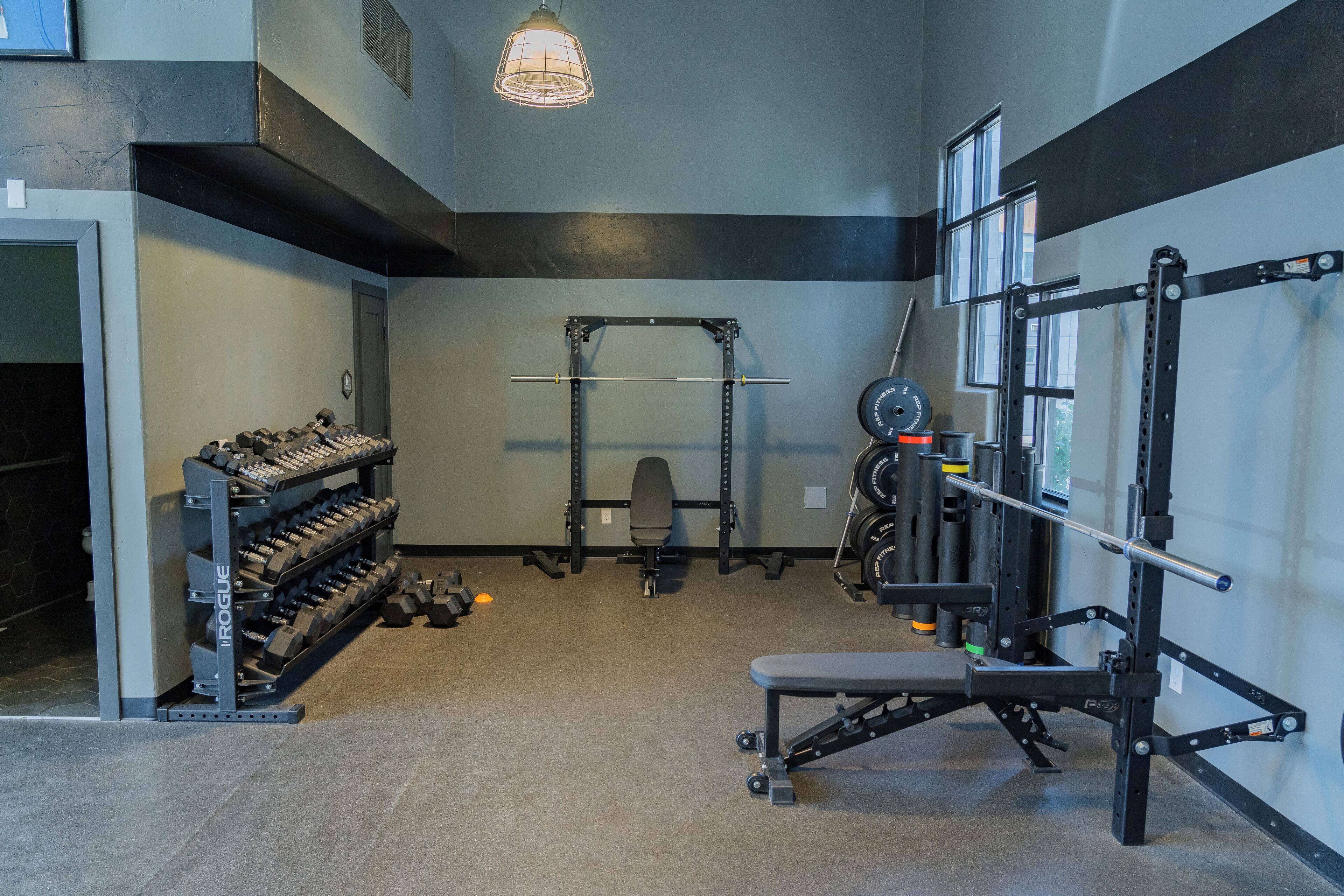 A gym with weight racks, a bench, and a squat rack.
