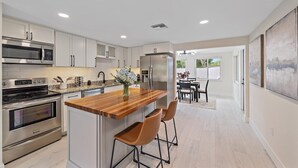 Una cocina moderna con electrodomésticos de acero inoxidable, una isla de madera y un comedor con vistas.