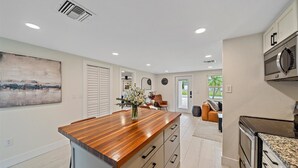Una cocina moderna con una isla de madera, electrodomésticos de acero inoxidable y vistas al exterior.