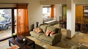 A living room with a sofa, coffee table, and a dining area with chairs and a table. - Beautiful 3-Bed  Sea Front Villa in Agios Nikolaos (Agios Nikolaos)