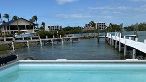 Una piscina con un bote de basura blanco, un muelle que se adentra en el agua y edificios al fondo.