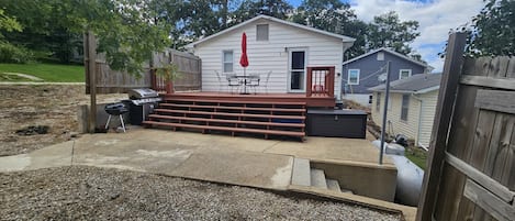 A backyard with a wooden deck, barbecue grill, and outdoor seating area.