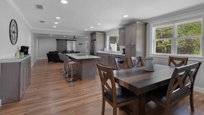 A spacious kitchen with a central island, wooden dining table, and bar stools.