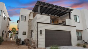 A modern two-story house with a garage, a balcony, and a pergola.