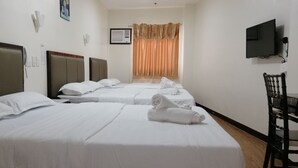 Habitación de hotel con cuatro camas, un televisor y una silla.