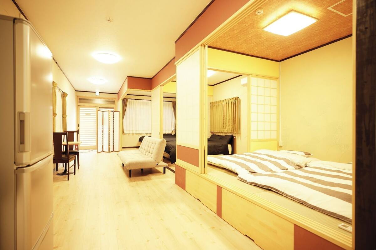 A hotel room with a bed, a chair, a desk, and a refrigerator.