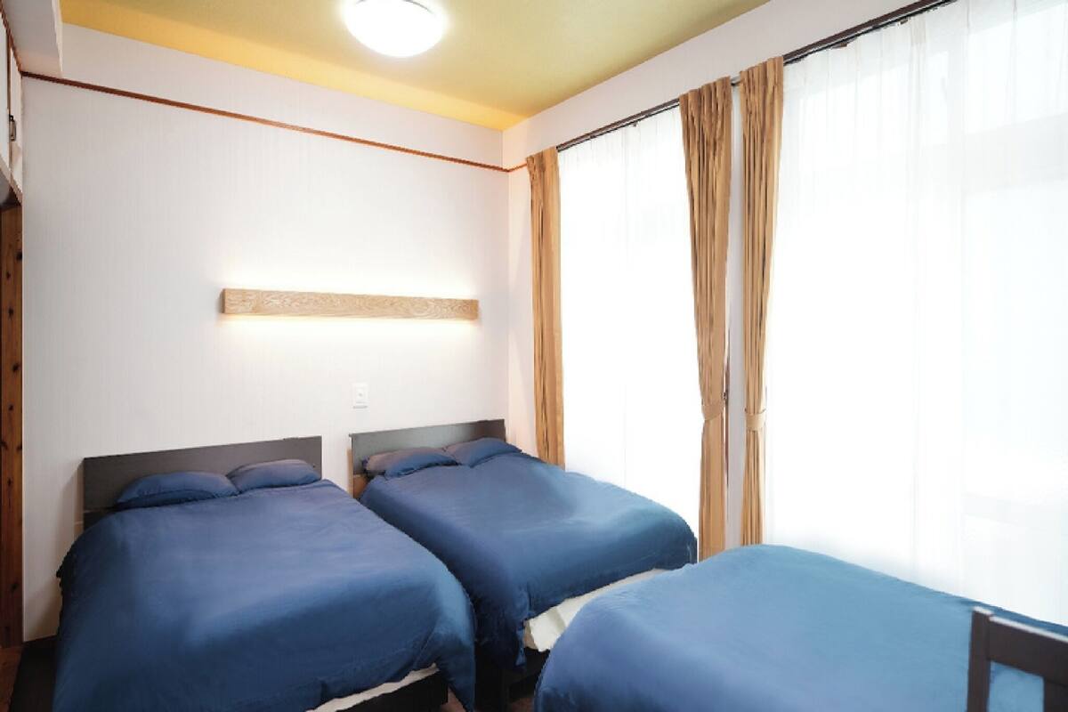 A hotel room with two beds, a wooden headboard, a light fixture, and a window with curtains.