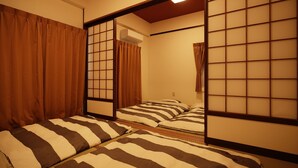 Una habitación tradicional japonesa con suelo de tatami, puertas correderas shoji y una cama baja con ropa de cama a rayas.