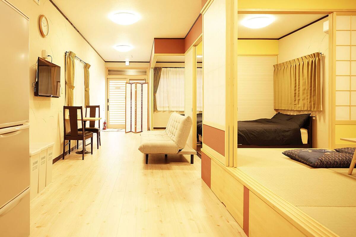 A compact hotel room with a kitchenette, a dining area, and a bed.