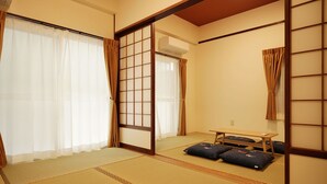 Una habitación japonesa tradicional con suelo de tatami, puertas correderas, una pequeña mesa y cojines.