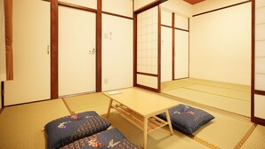 Una habitación japonesa tradicional con suelo de tatami, una mesa de madera baja y paneles shoji.