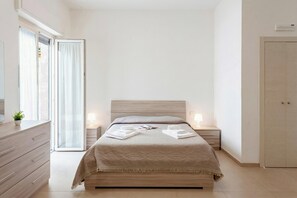 A bedroom with a bed, bedside tables, a dresser, a wardrobe, and a sliding glass door. - Suite 1 Ondina Viareggio 200m from sea, Viareggio, Italy (Viareggio)