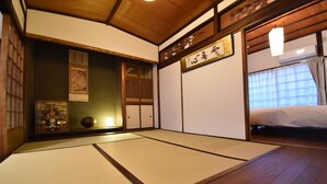 A traditional Japanese room with tatami flooring, a shoji screen, and a futon bed. - Quaint House Naoshima (Naoshima)