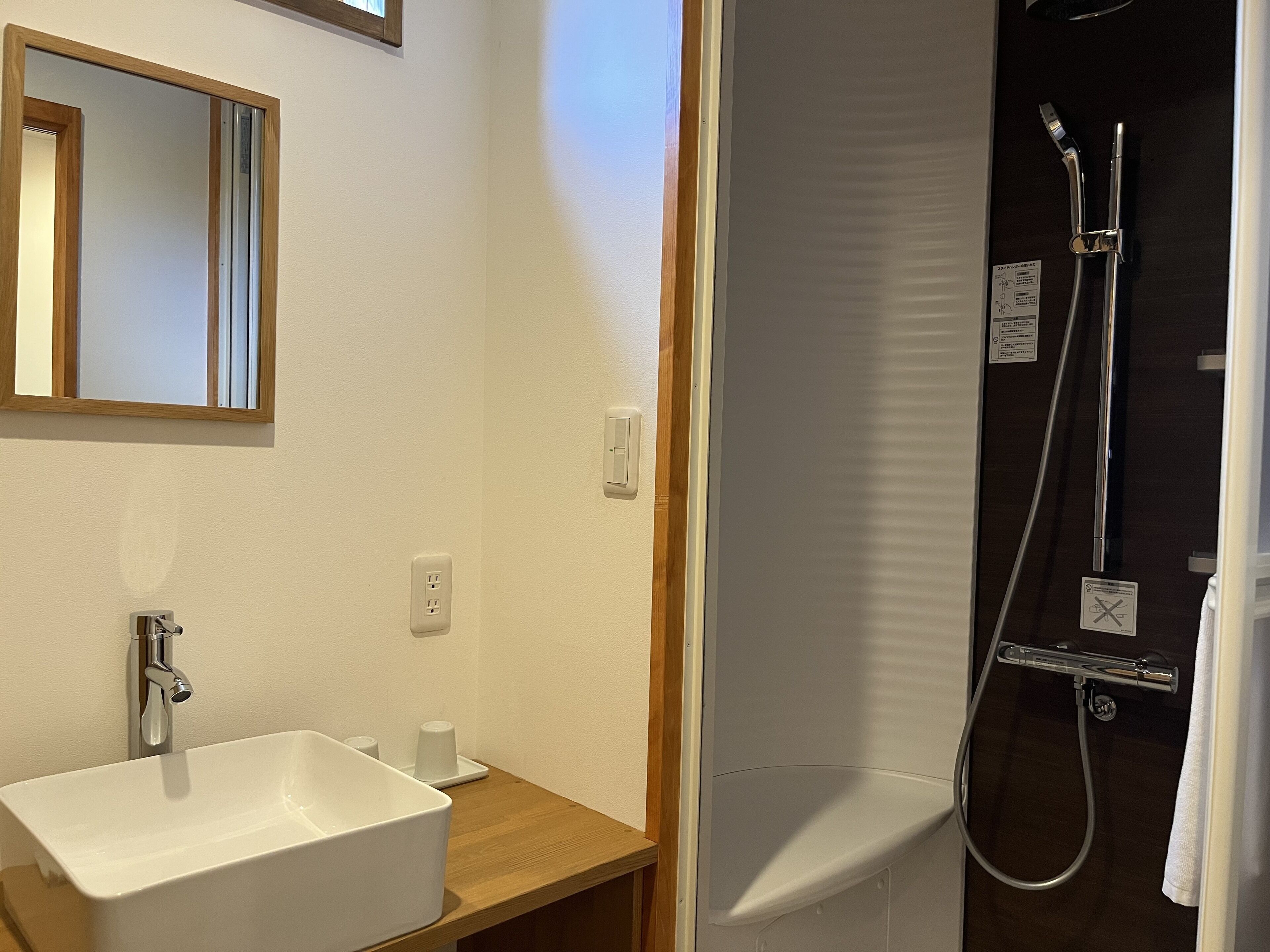 A bathroom with a white sink, a mirror, and a shower area with a glass door.