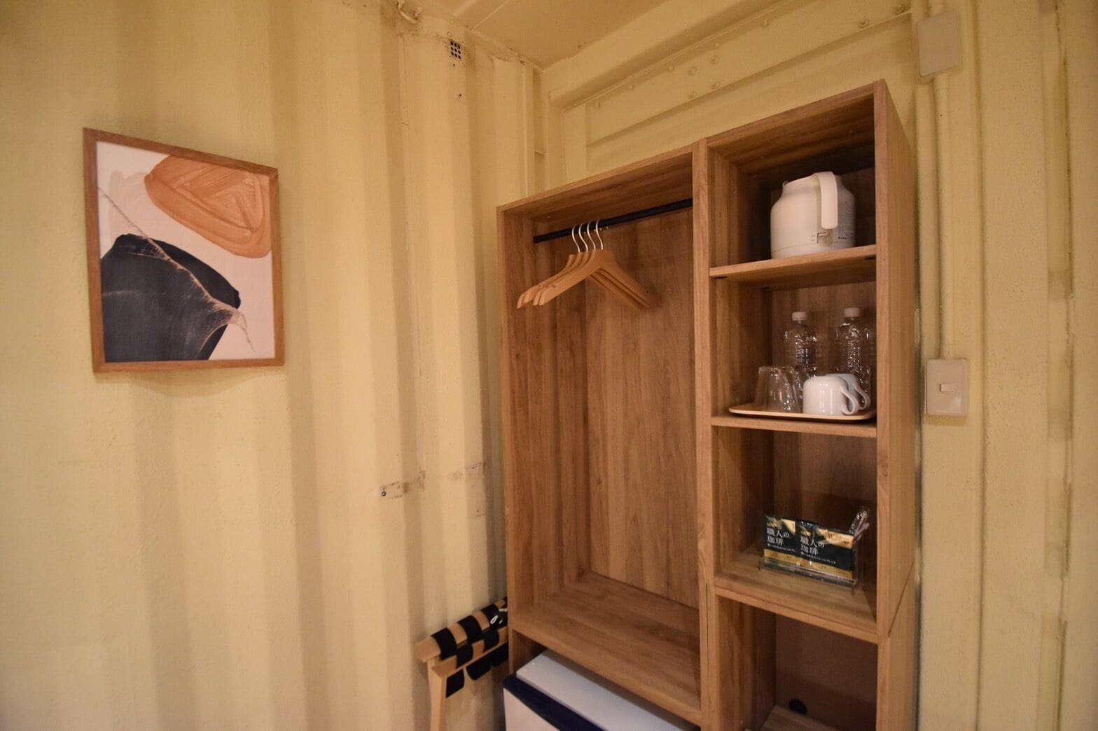 A wooden wardrobe with shelves, a hanging rod, and a small cabinet with items like bottles and a box.