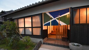 A traditional Japanese house with a sliding door, a stone lantern, and a small garden with rocks and plants. - Quaint House Naoshima (Naoshima)