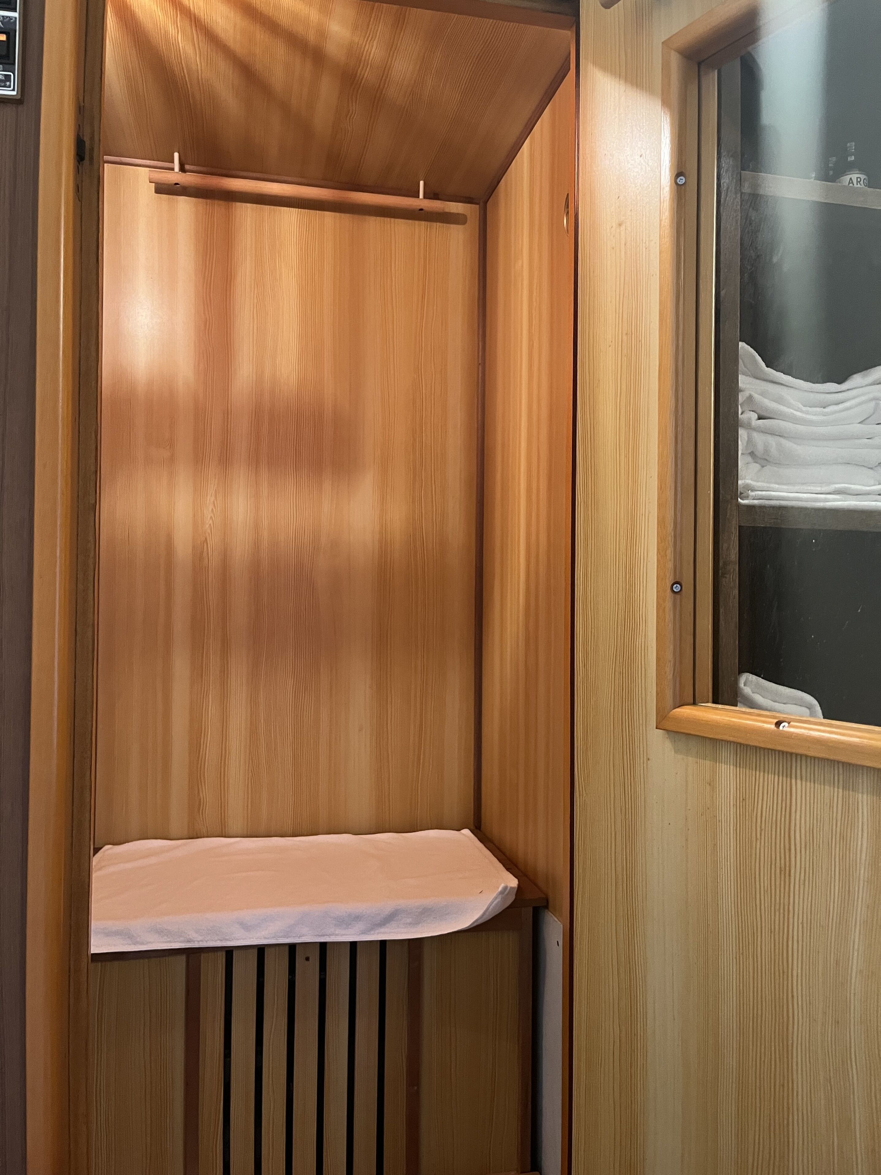 A wooden wardrobe with a mirror and a shelf.