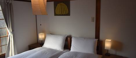 Una camera d'albergo con un letto grande, due comodini con lampade, un'opera d'arte appesa al muro e una finestra con tende.